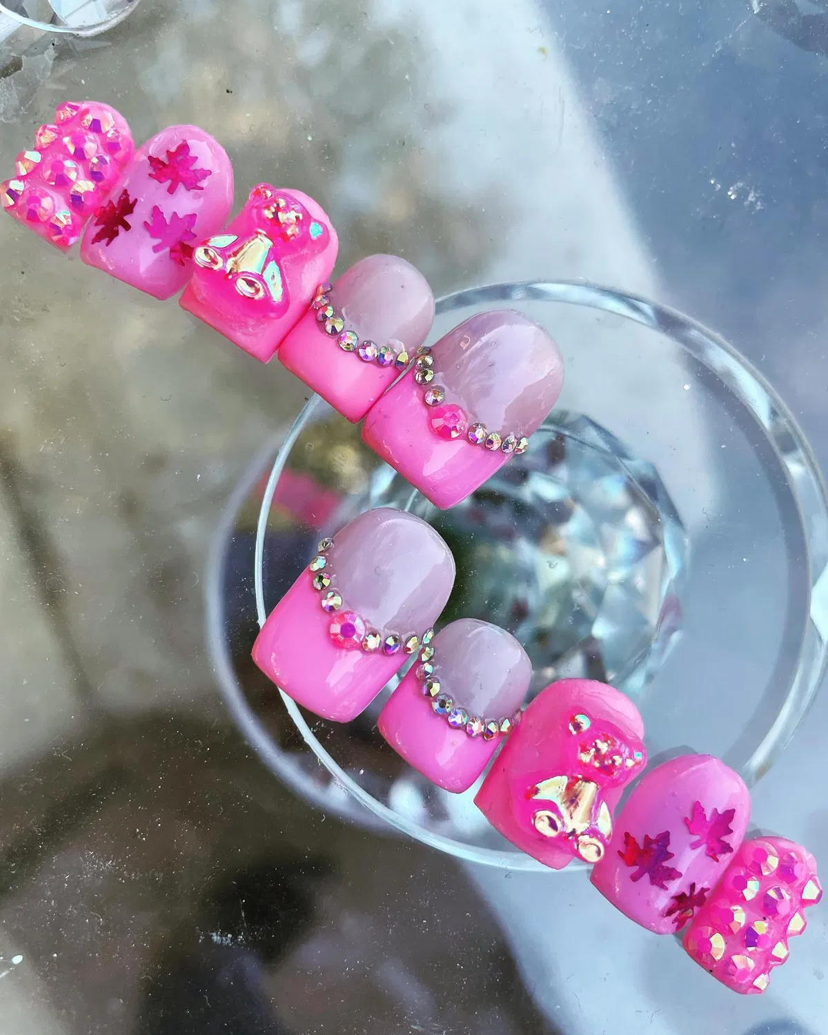 Pink ombrรฉ press-on style with bows, leaves, and rhinestones
