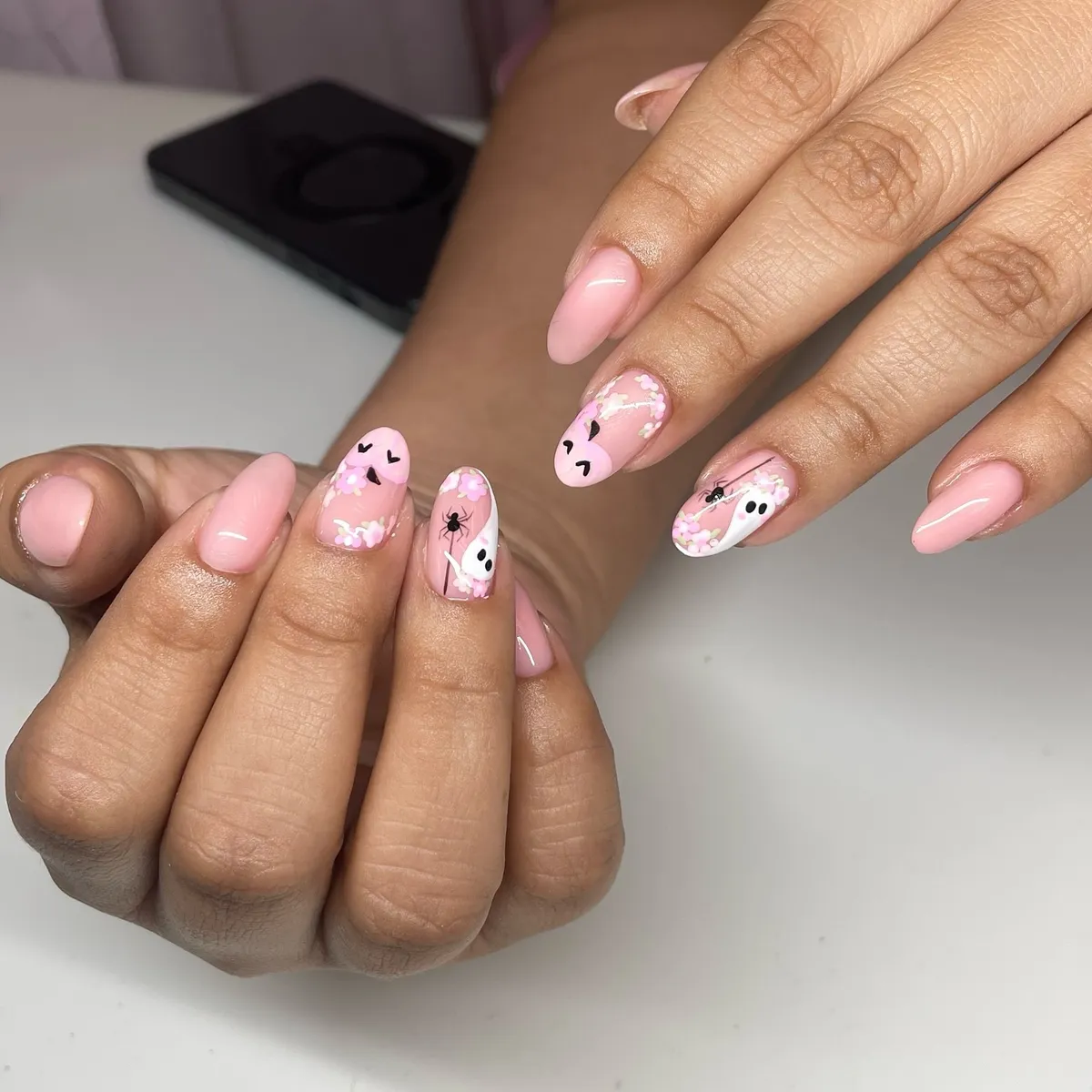 Soft pink almond nails with confetti and tiny spooky accents