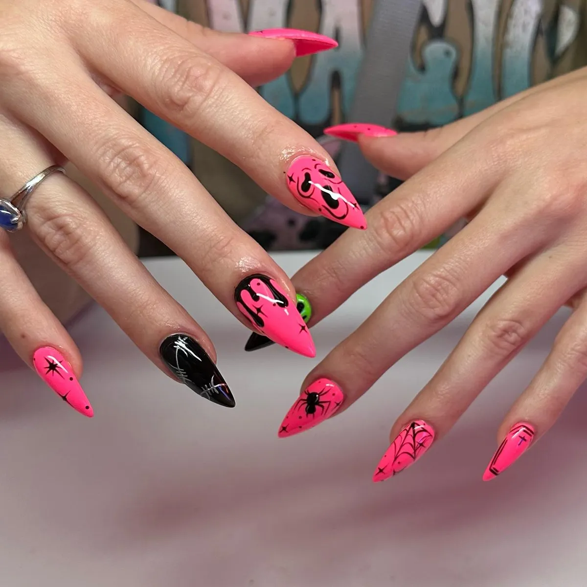 Neon pink stiletto nails with spiderwebs and spider