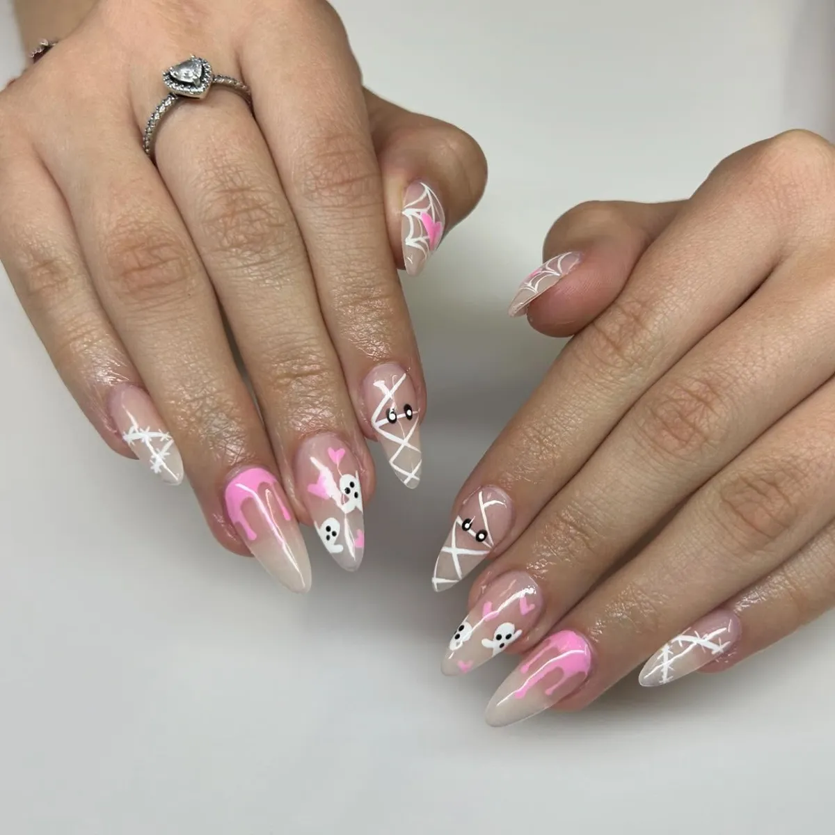 Sheer nude almond nails with pink drips, ghosts, and mummy wraps