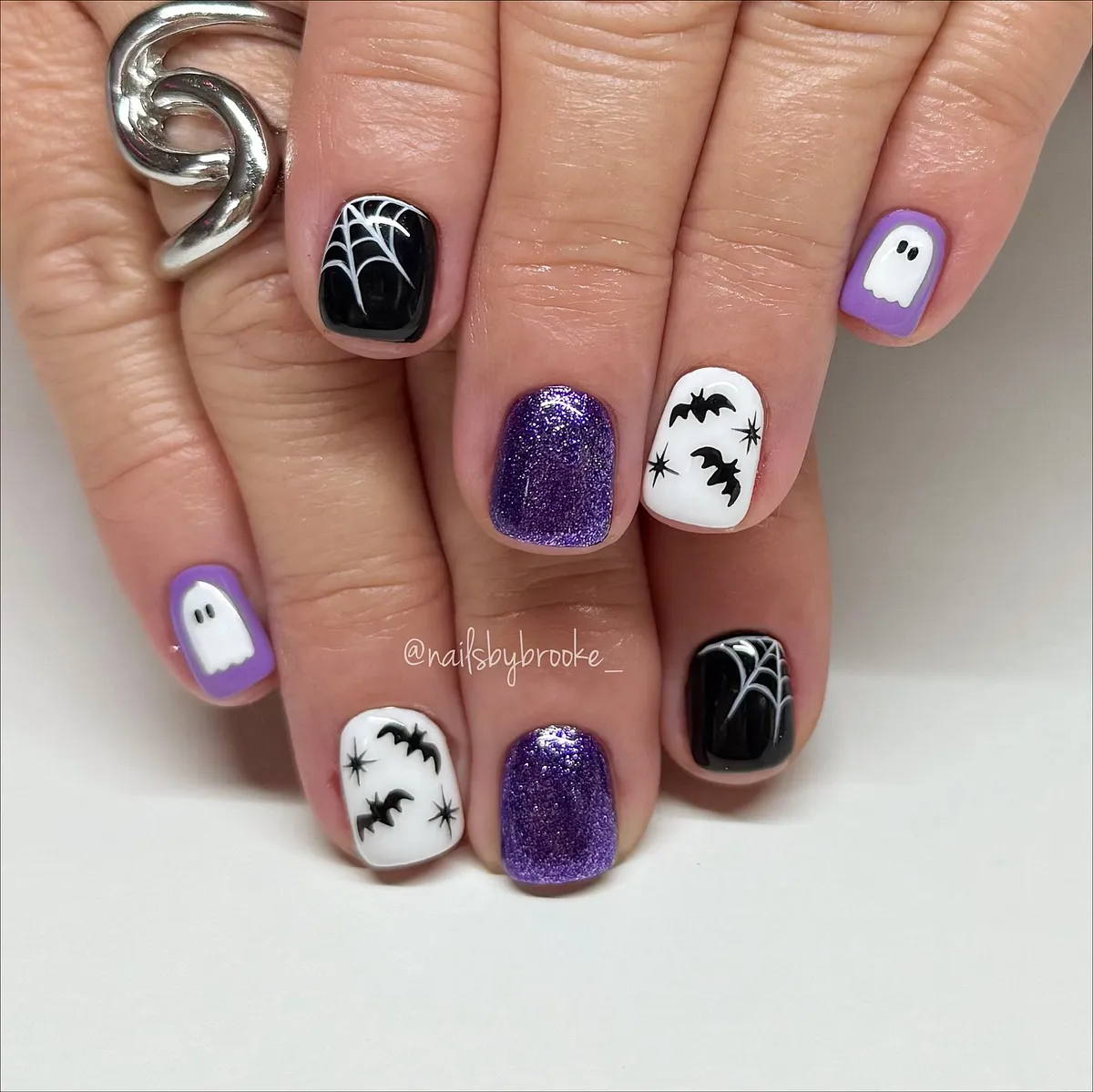 Purple, black, and white graphic accents (webs, bats, ghost)