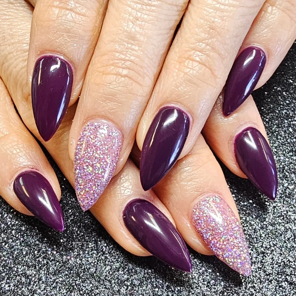 Deep plum stiletto nails with pink-lilac glitter accents