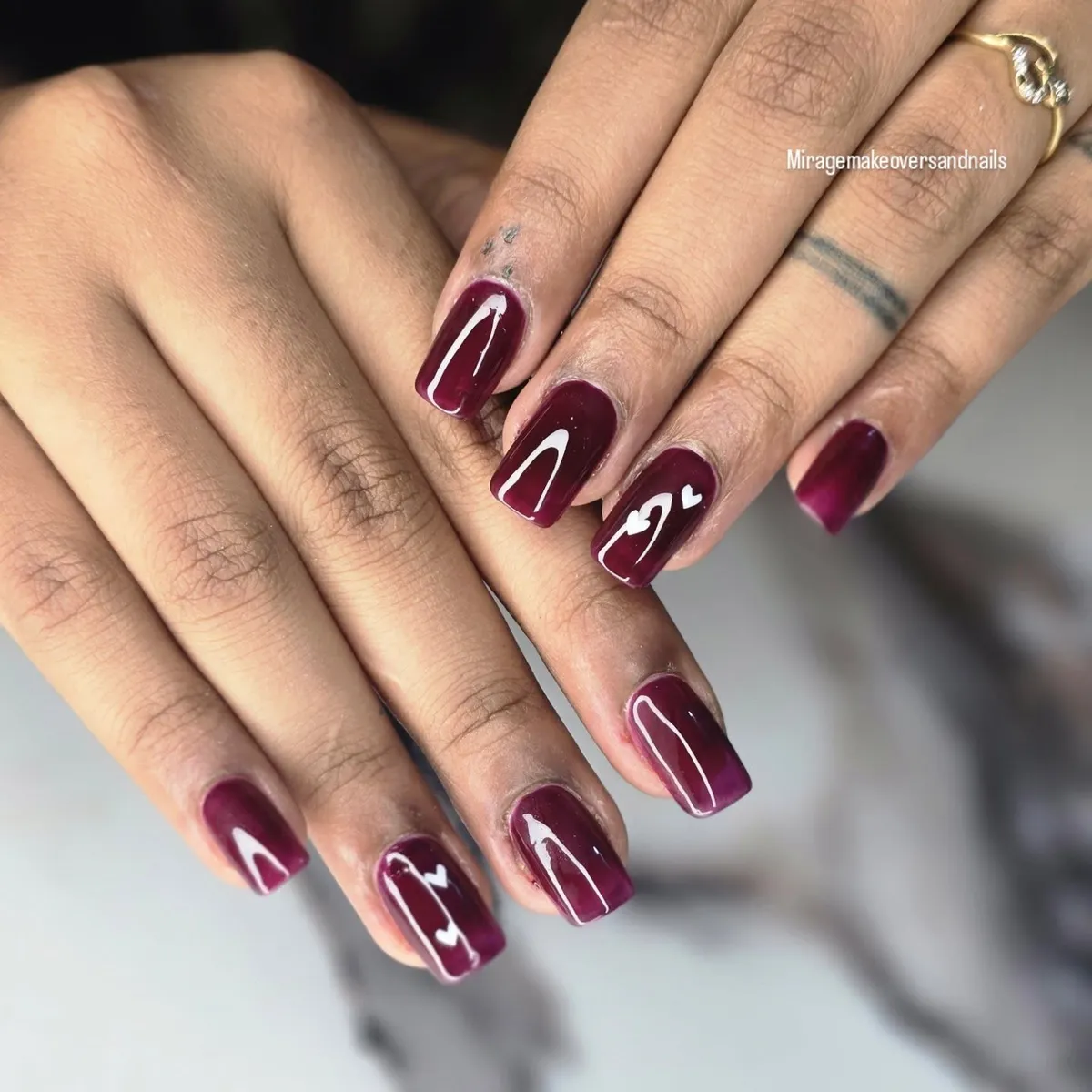 Glossy wine-plum nails with tiny white hearts