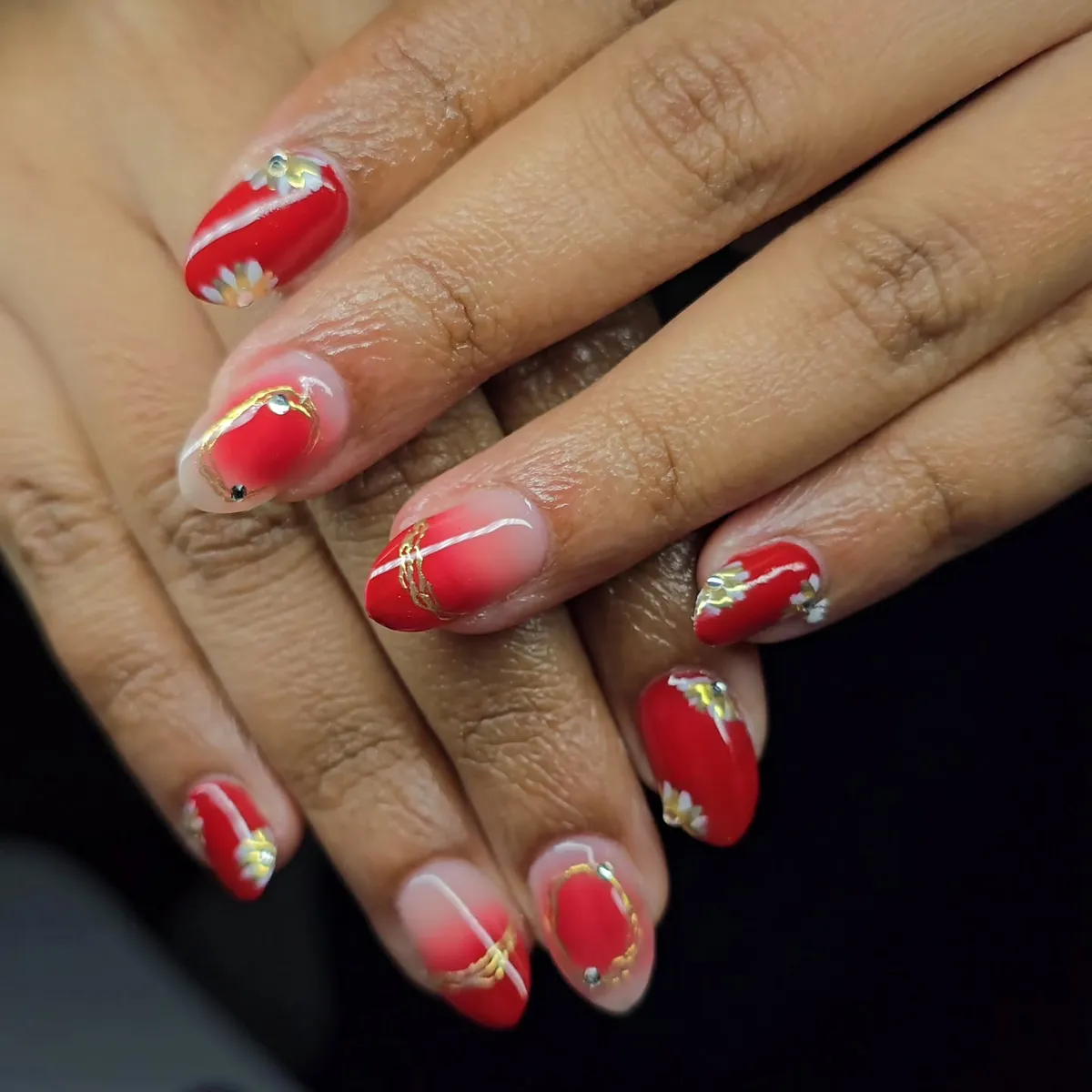 Red gradient nails with curved lines and small floral details