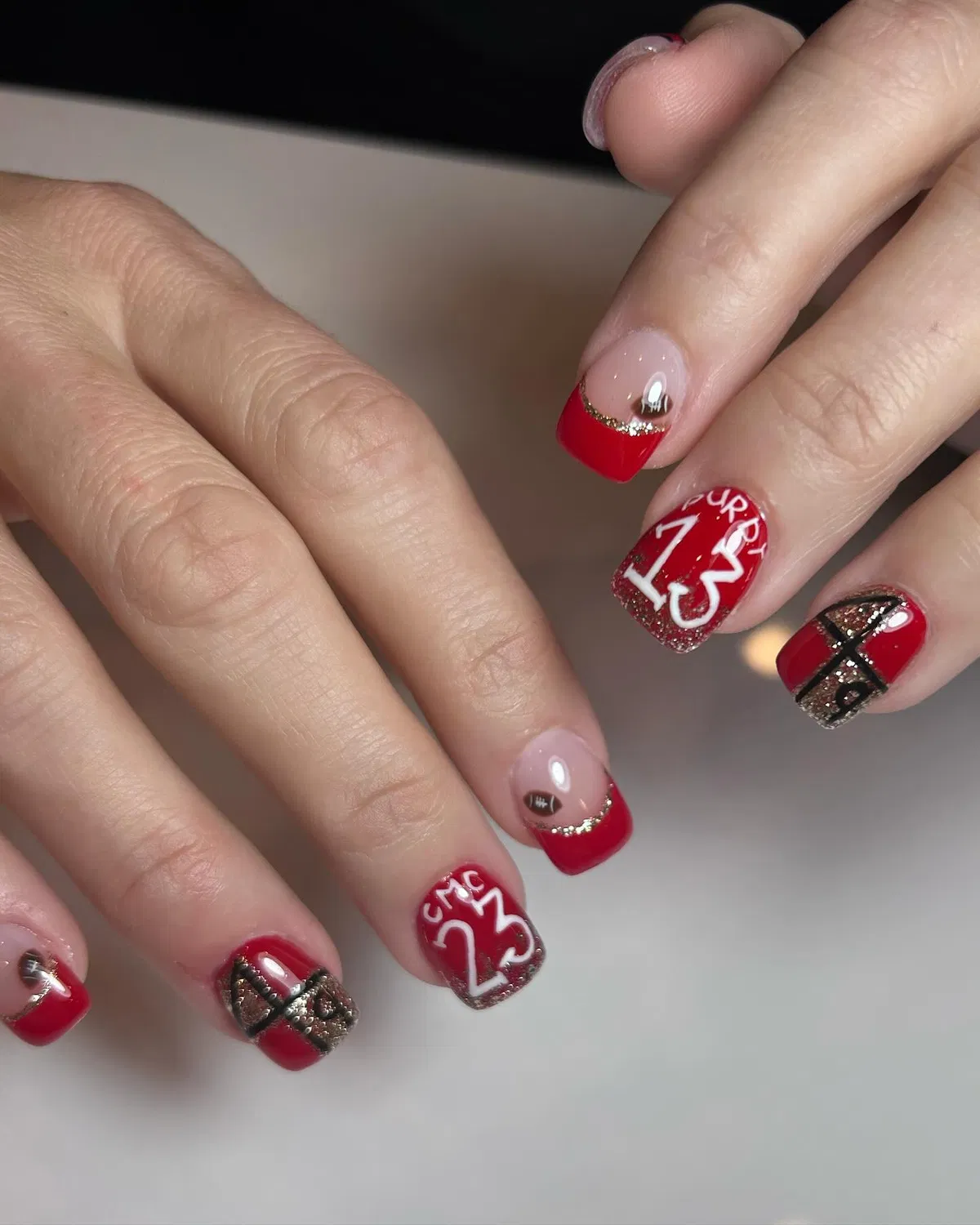 Red French tips with football icons and a '13' accent nail