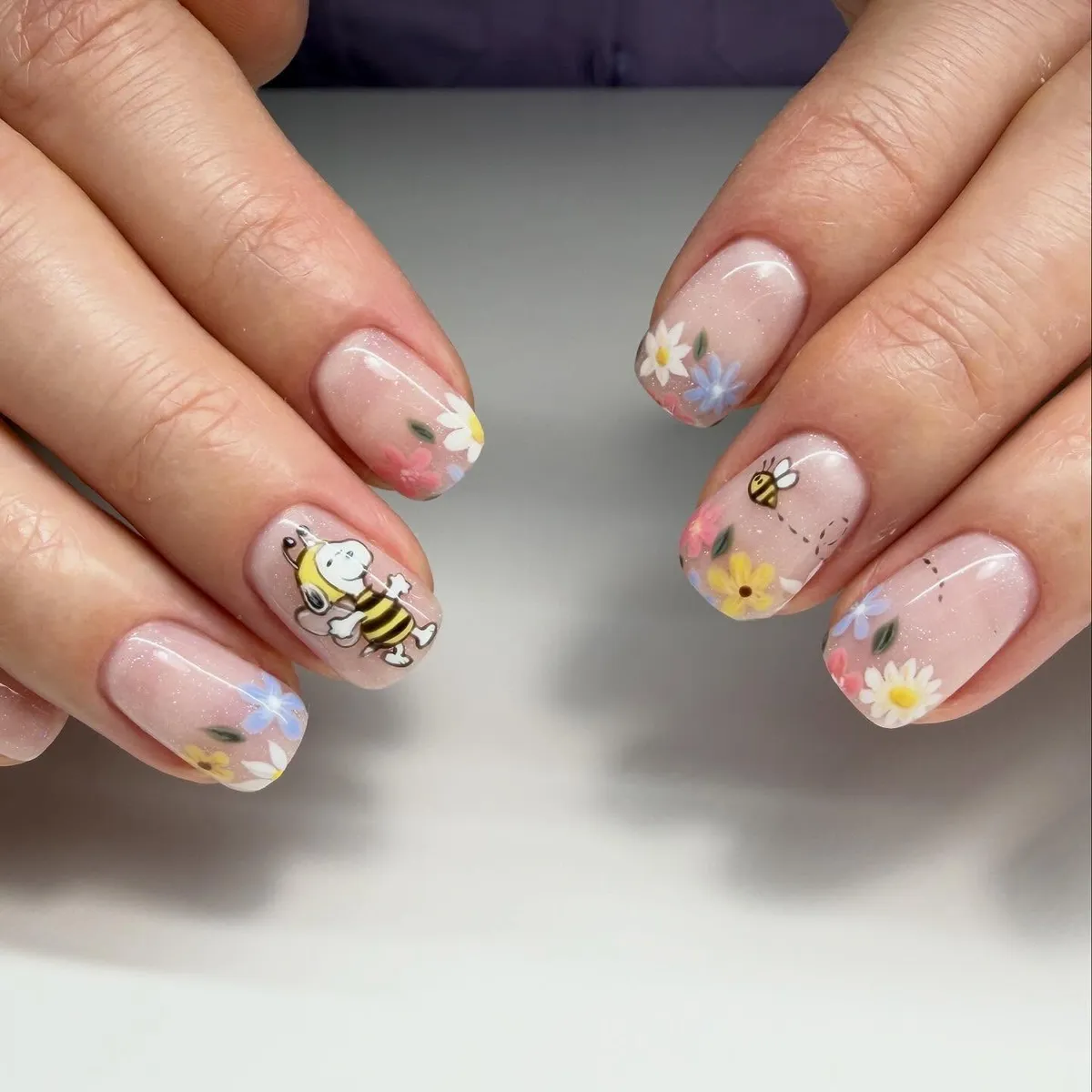 Soft floral nails with bee-themed cartoon accents