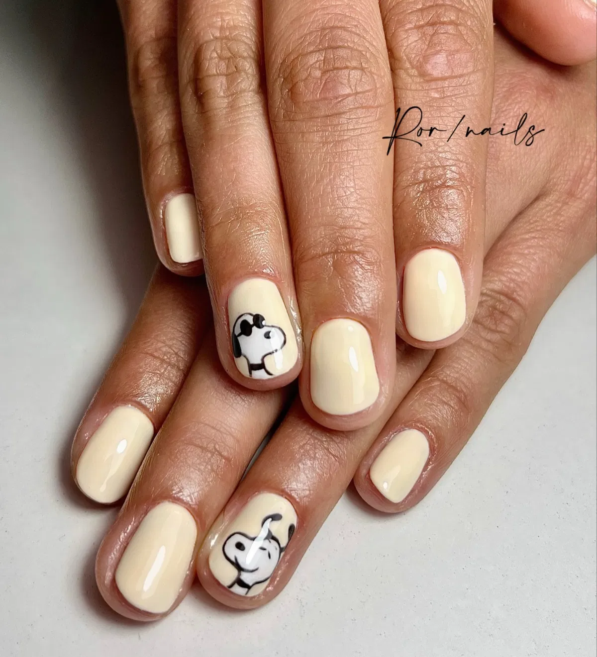 Simple cream manicure with minimal cartoon face accents