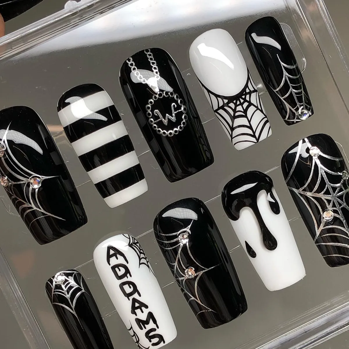 Black-and-white press-on set with webs, drips, stripes, and “ADDAMS” text