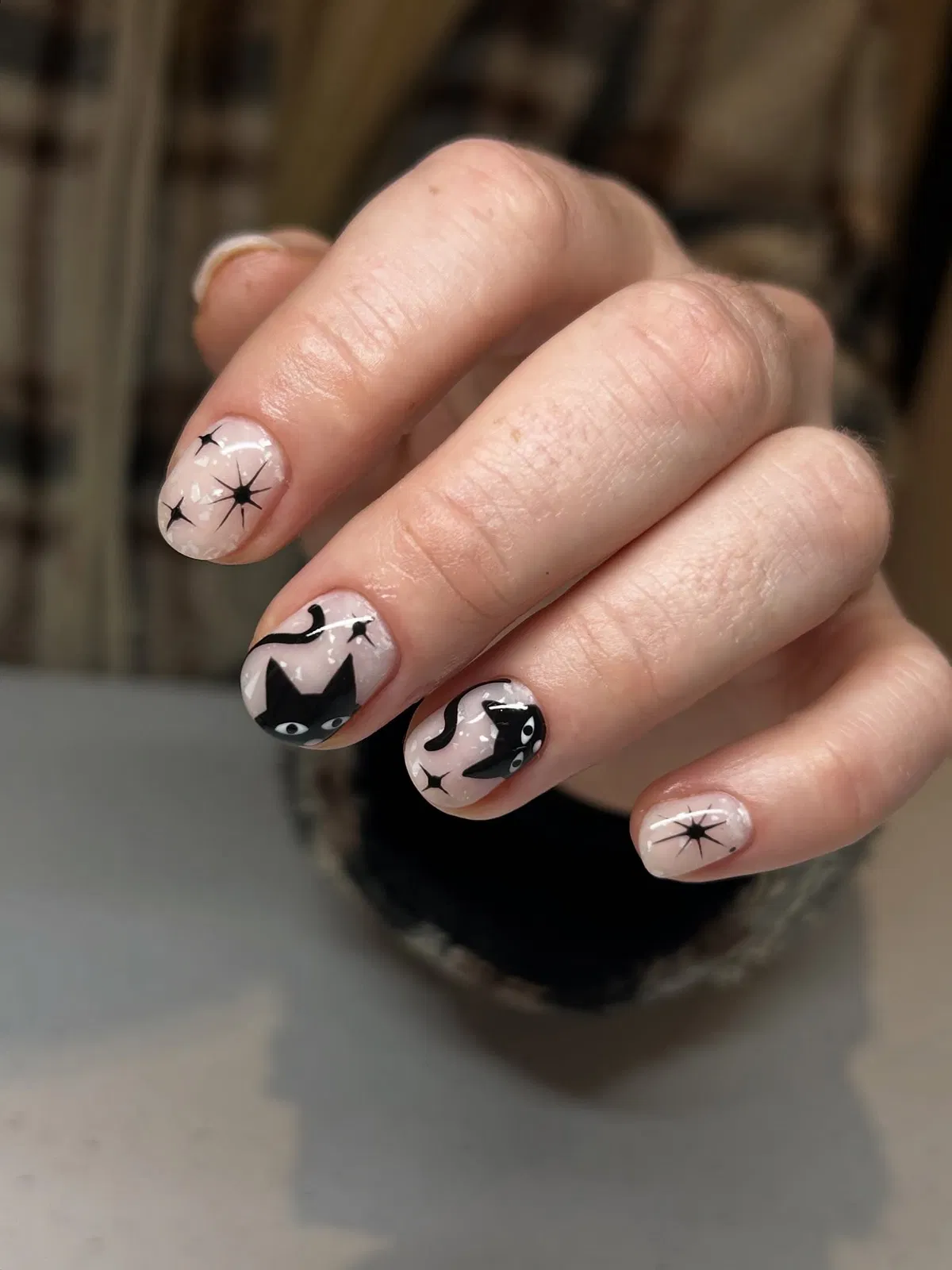 Minimal nude nails with black cats and starbursts