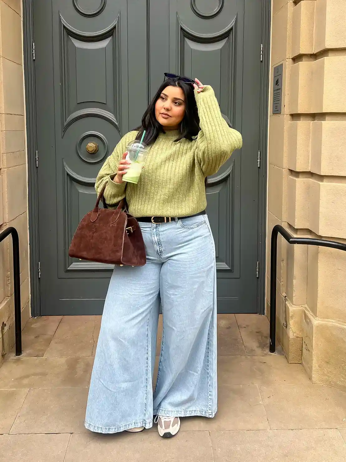 Ribbed green sweater with wide-leg jeans and brown bag