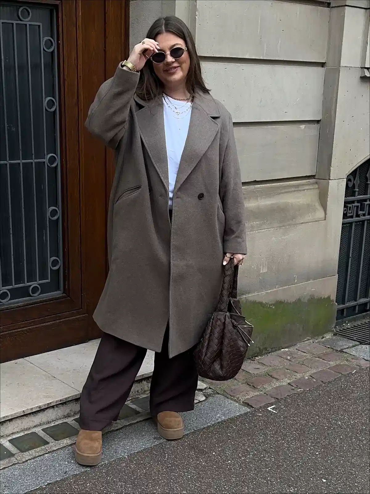 Long neutral coat with dark wide-leg pants and platforms