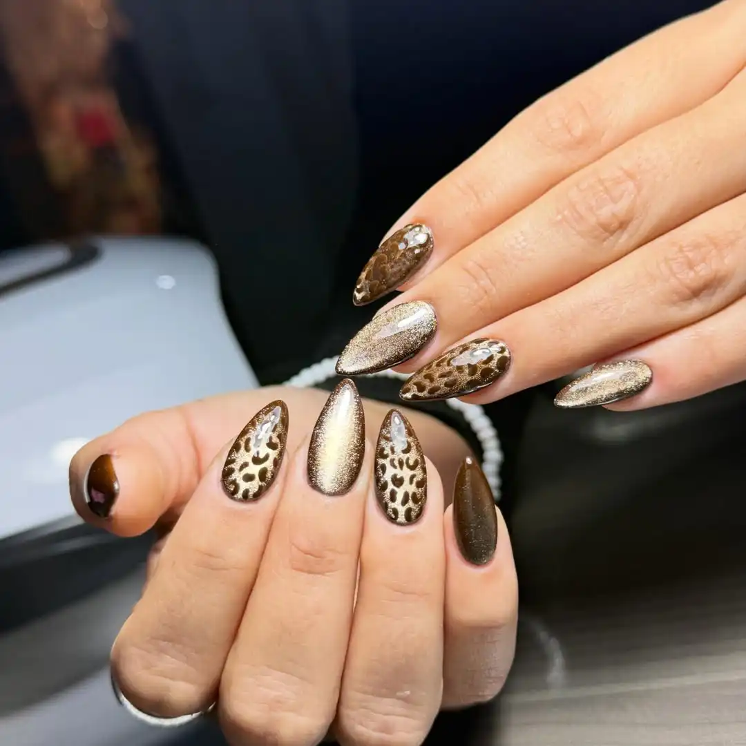 Almond animal-print browns paired with metallic gold nails