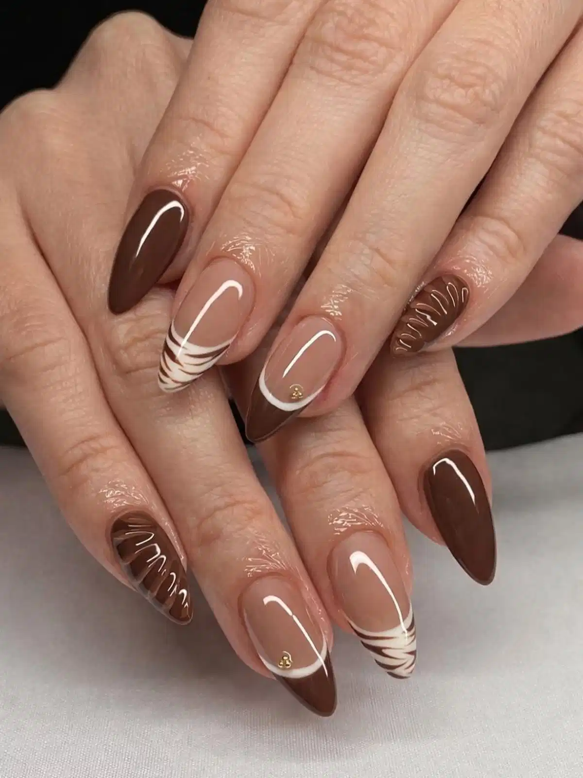 Brown French tips with white curves, striped tips, and subtle gold studs
