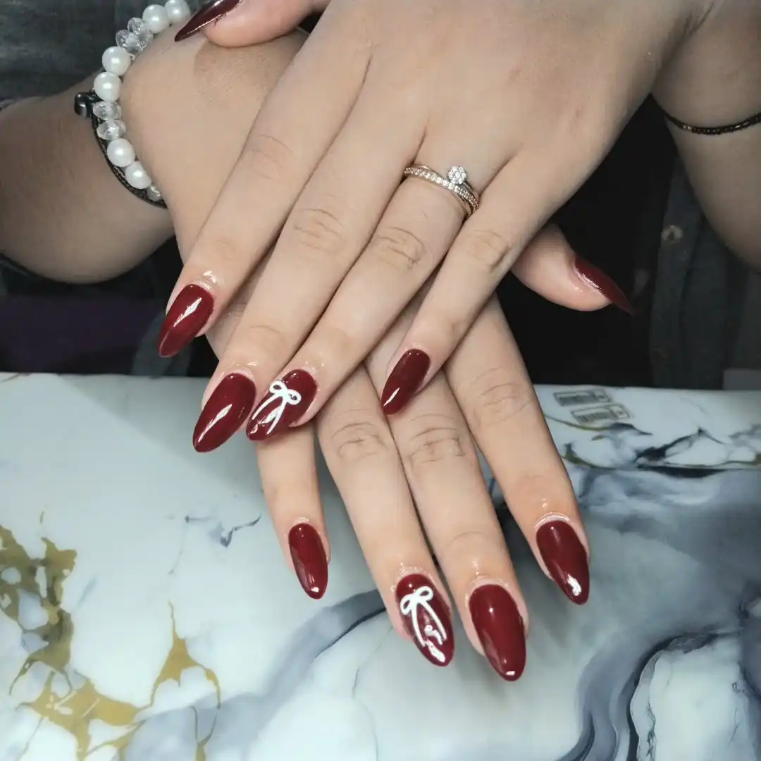 Stiletto Maroon Nails with White Bow Line Art