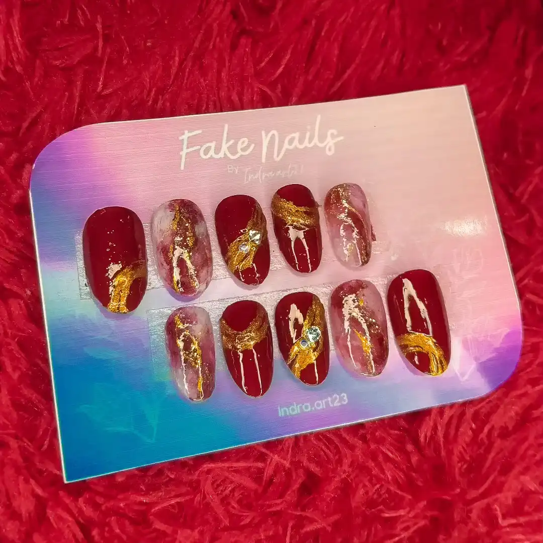 Maroon press-on set with gold swirls and translucent marbling