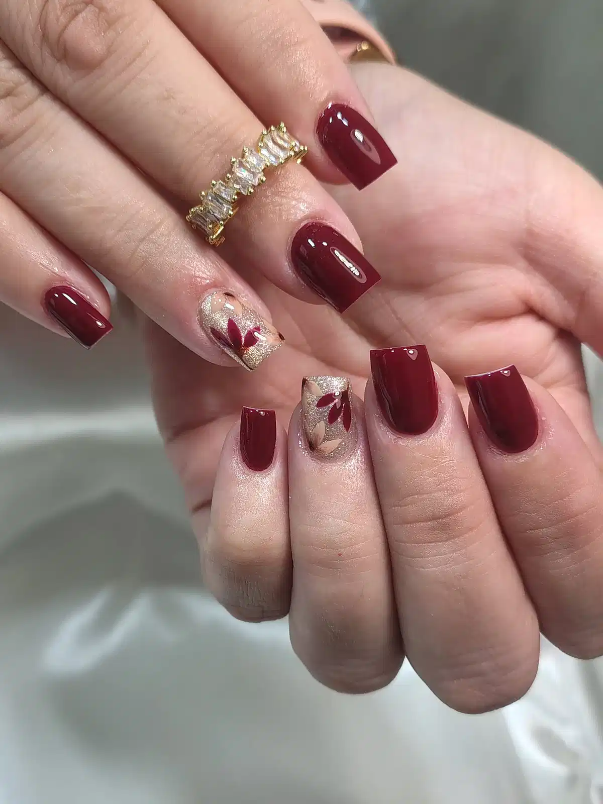 Maroon square nails with gold-glitter leaf accents