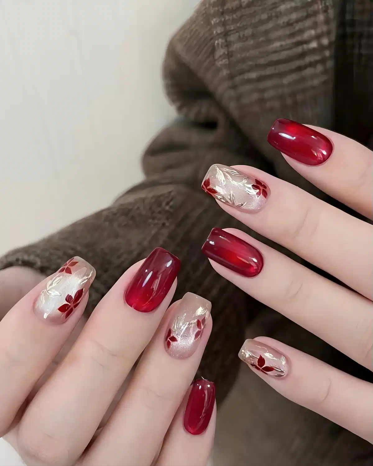 Translucent maroon and nude nails with red leaf accents