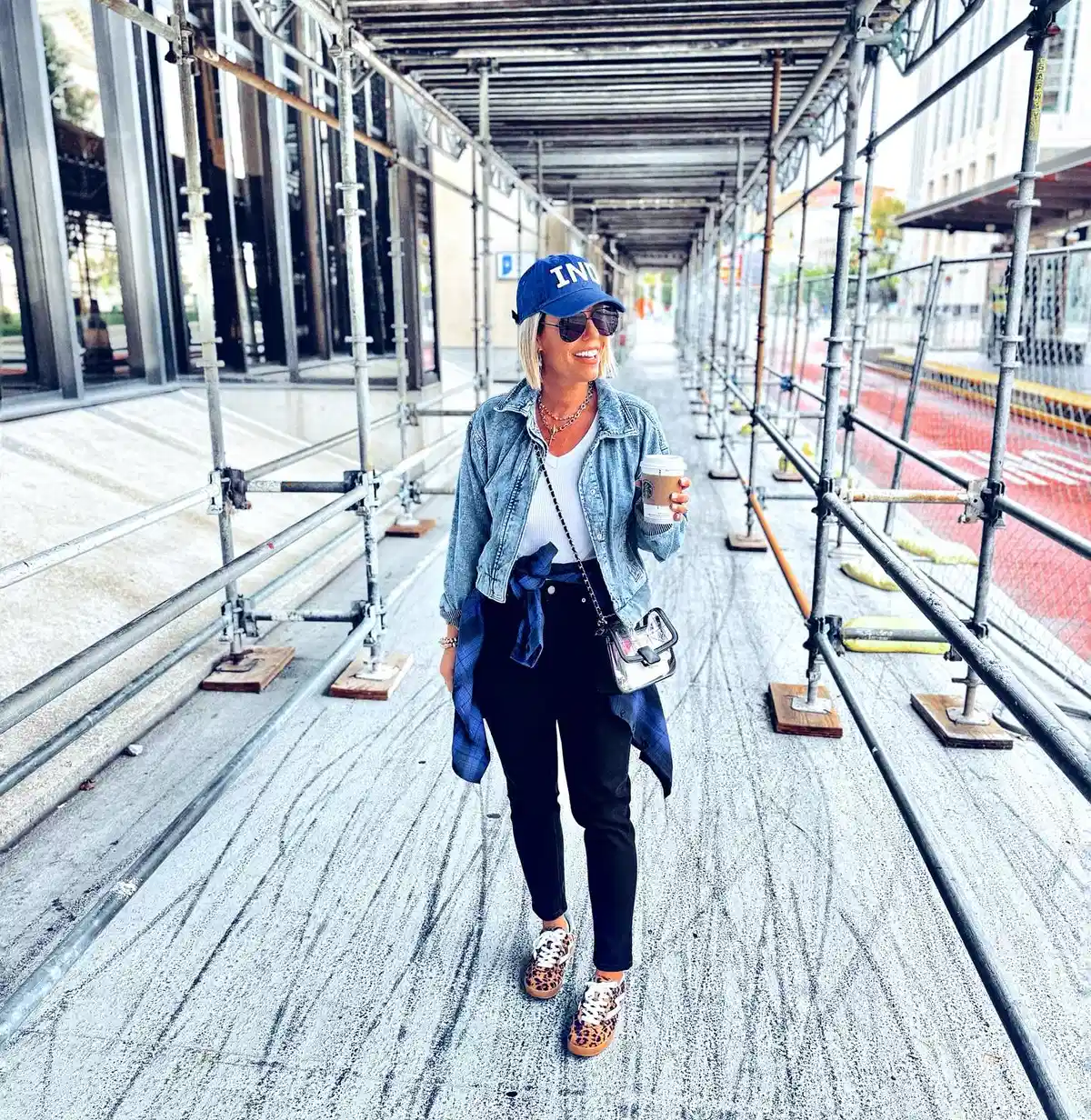 ‘IND’ cap with denim jacket, black pants, and leopard sneakers