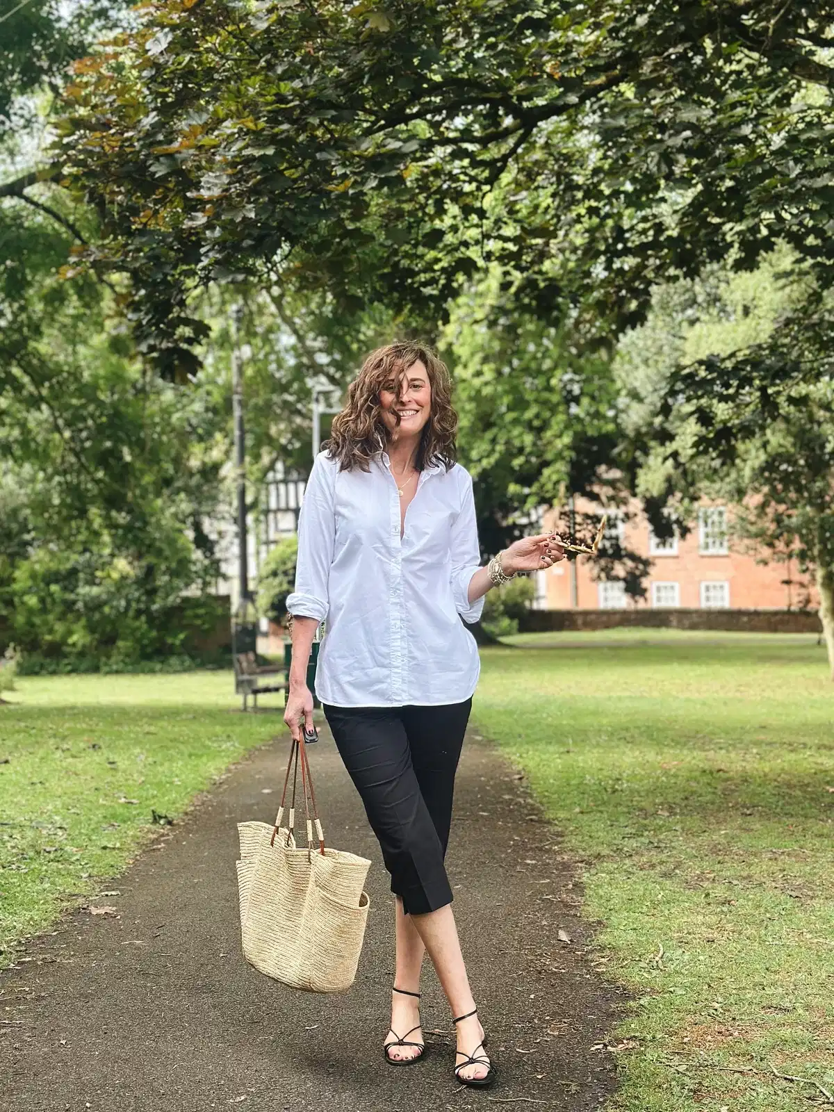 White button-up with black cropped pants and woven tote
