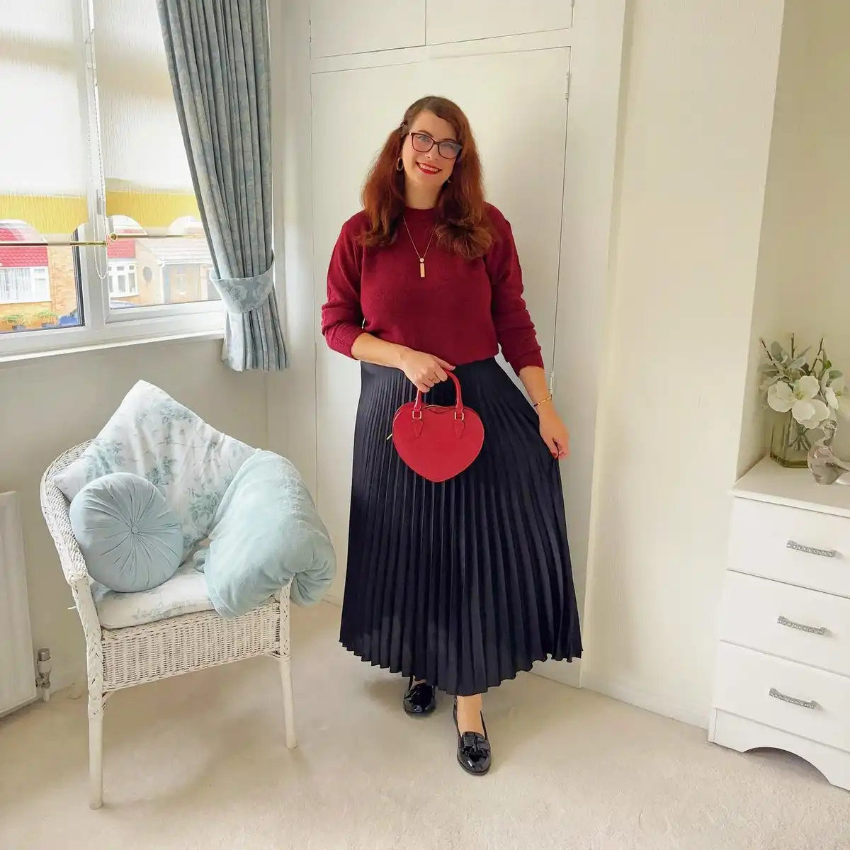 Burgundy sweater with black pleated skirt and heart bag