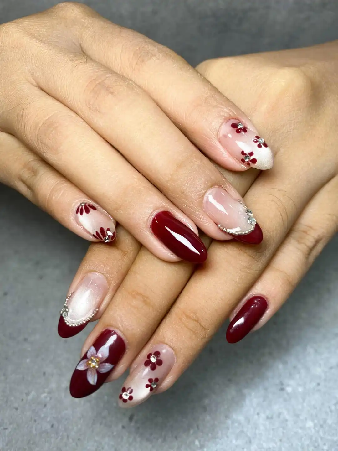 Maroon French tips with small floral and rhinestone accents