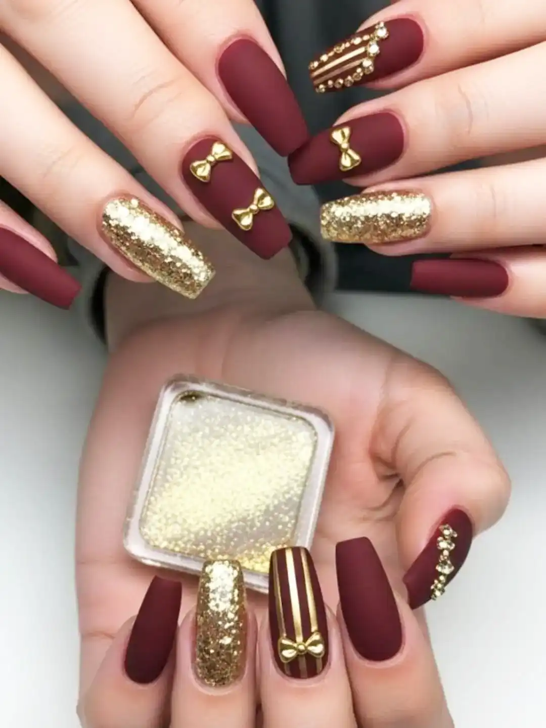 Matte maroon squares with gold bows, stripes, and full glitter accent