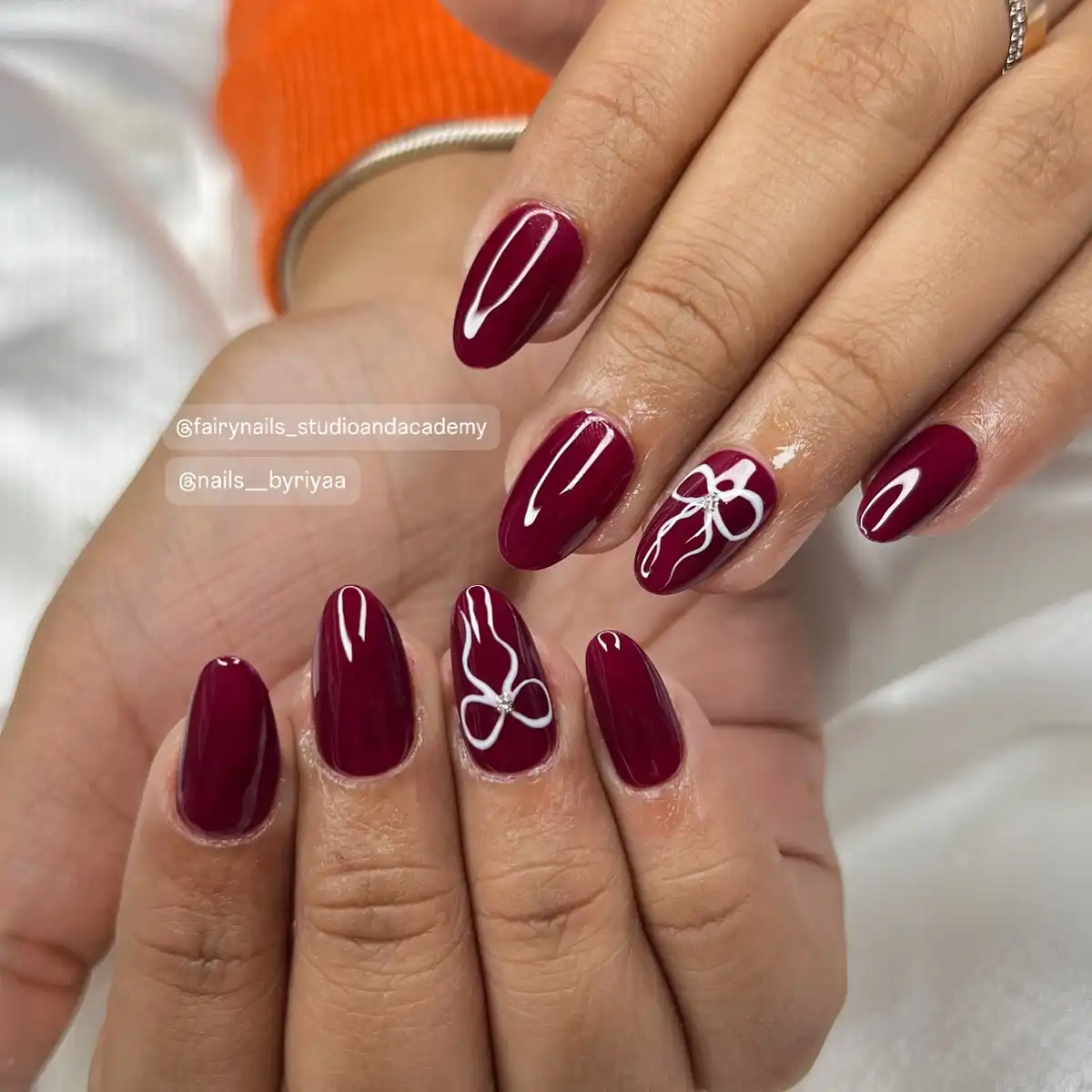 Glossy maroon nails with white bow outlines