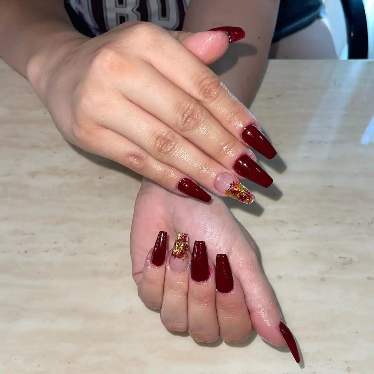 Glossy burgundy coffin nails with a confetti-glass accent