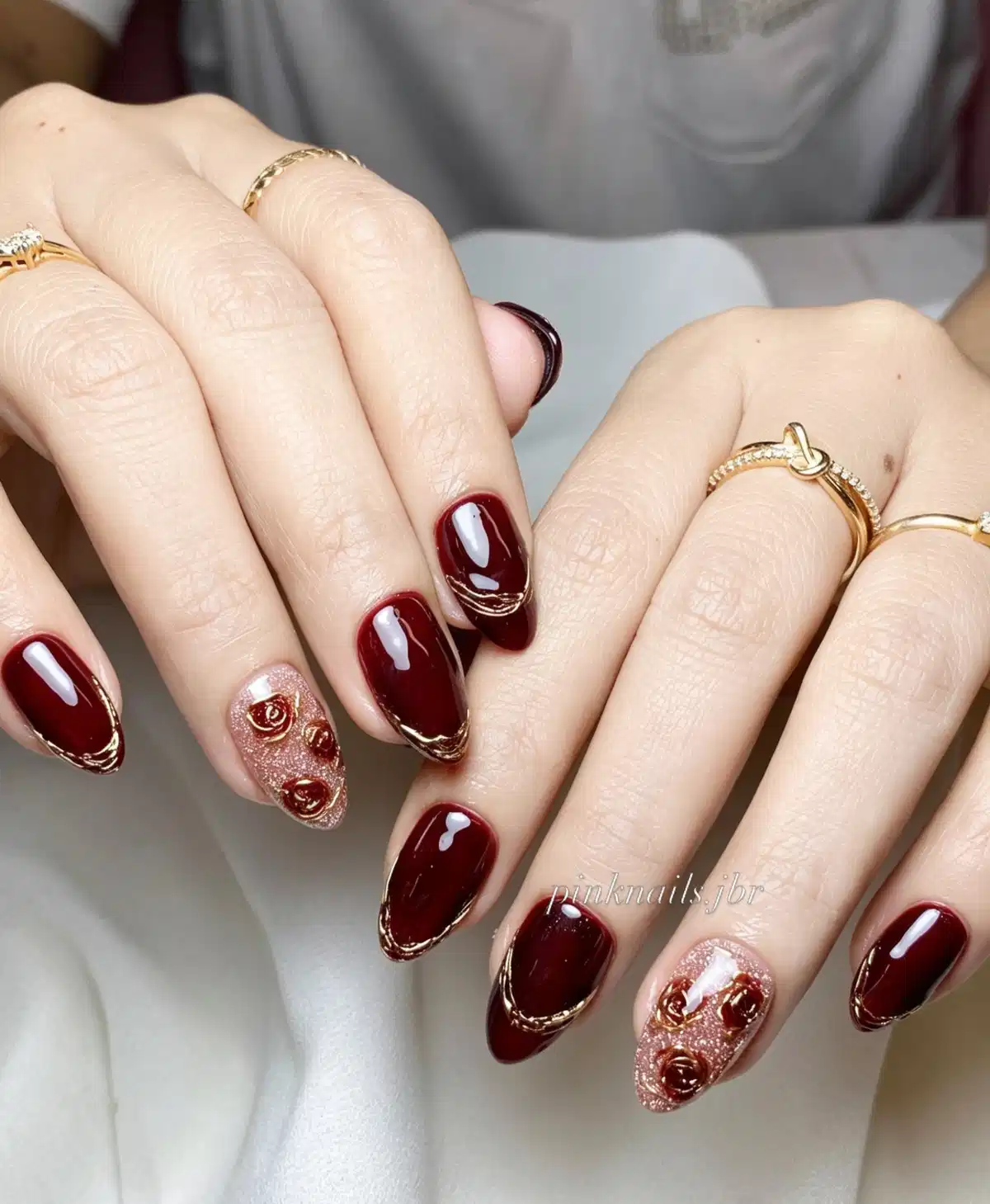 Burgundy almond nails with gold outlines and rose-glitter rose accents
