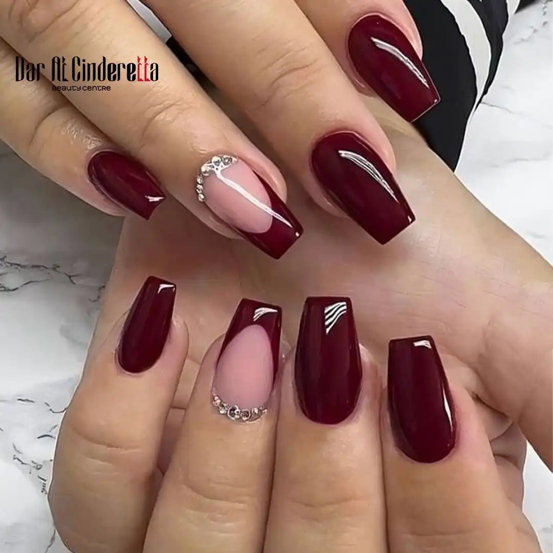 Maroon coffin nails with nude negative-space and rhinestone arcs