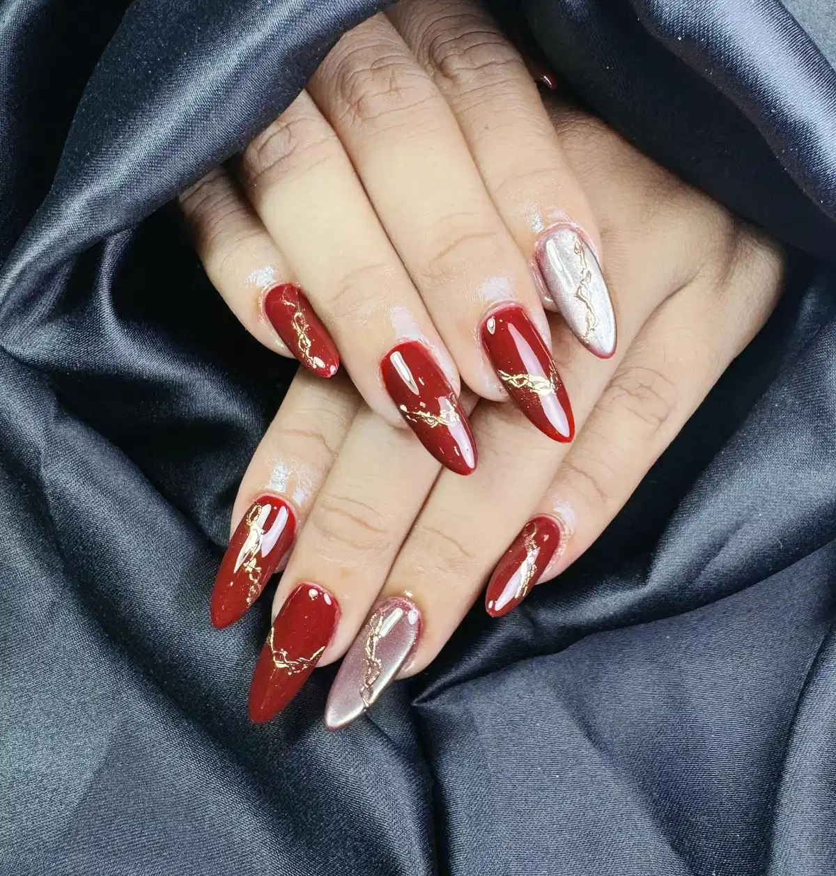 Long maroon stilettos with gold streaks and silver accent nails