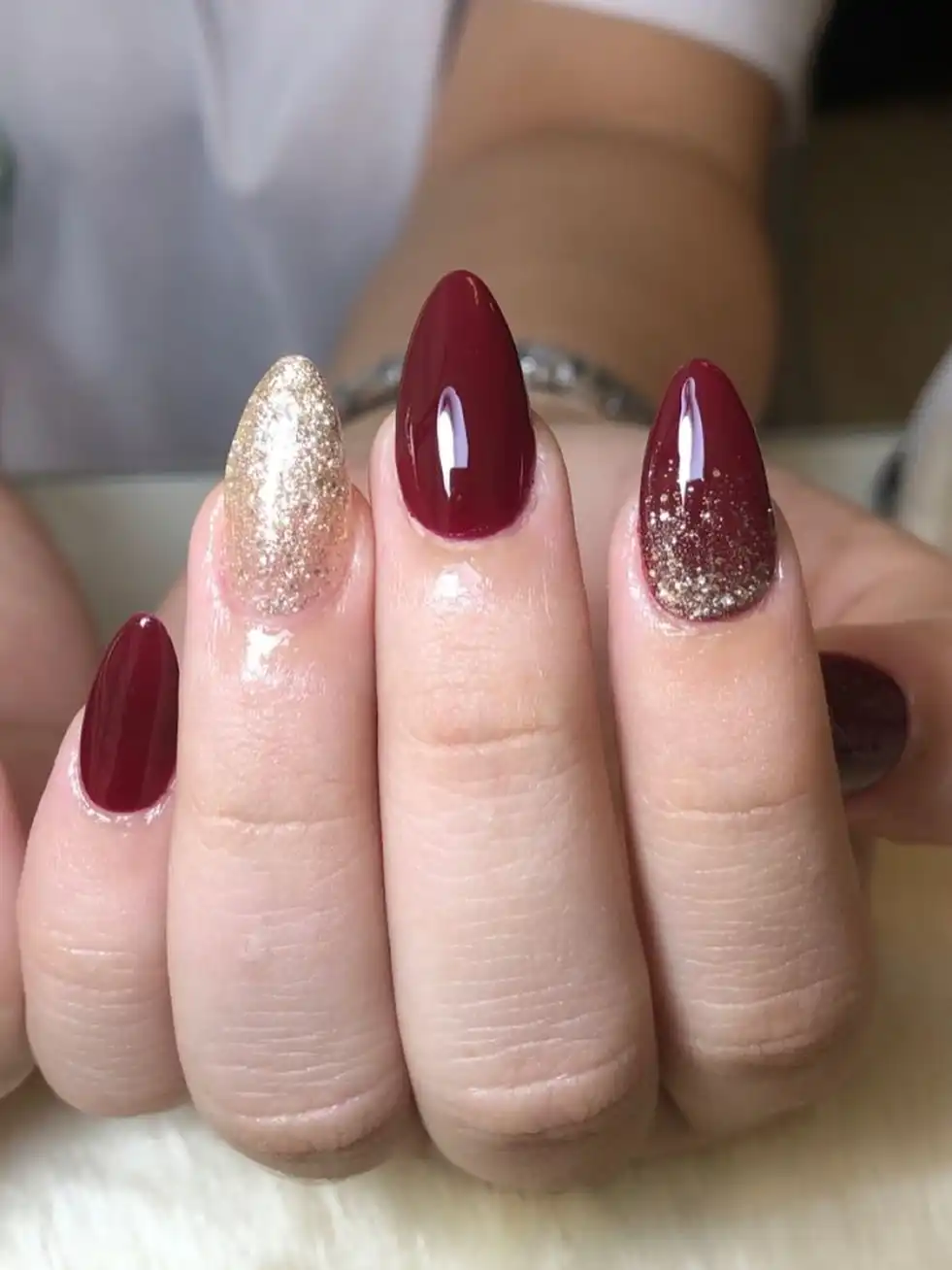 Maroon almond nails with full-glitter gold accents