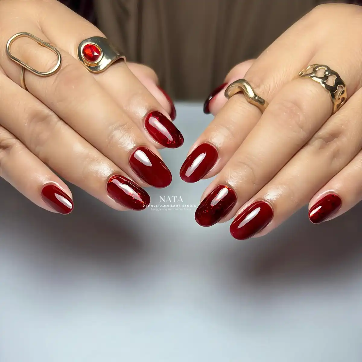 Glossy deep maroon nails with subtle marbled swirls