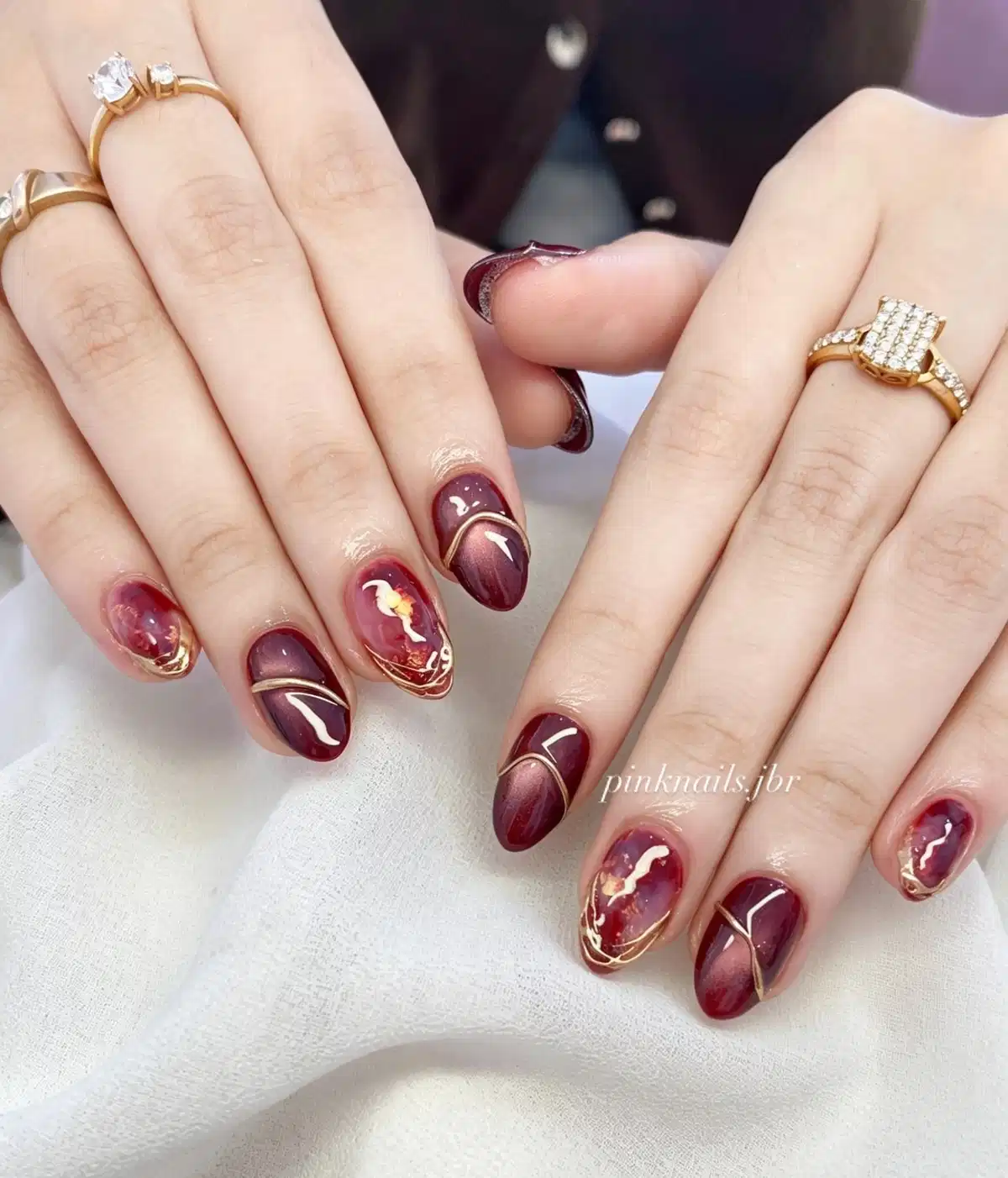 Maroon almond nails with gold curved line art