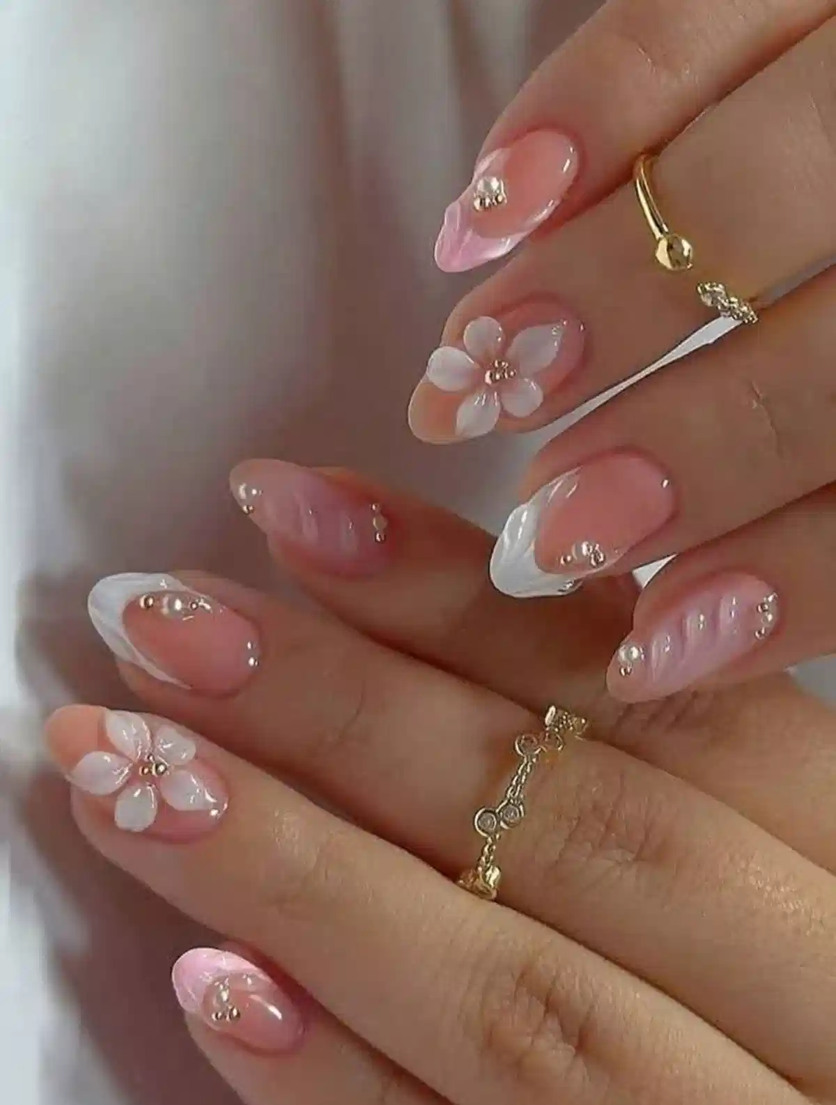 Pink almond nails with white French tips, 3D flowers, and rhinestone accents