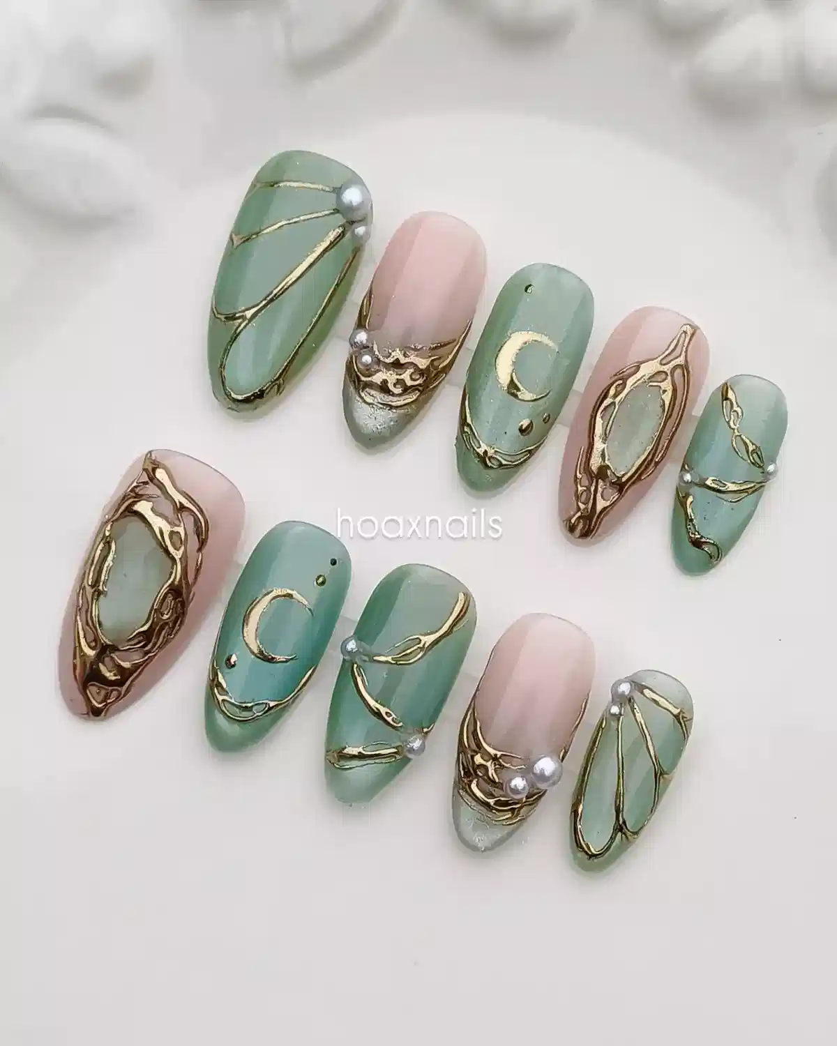 Muted green and nude nails with gold linework and pearl accents