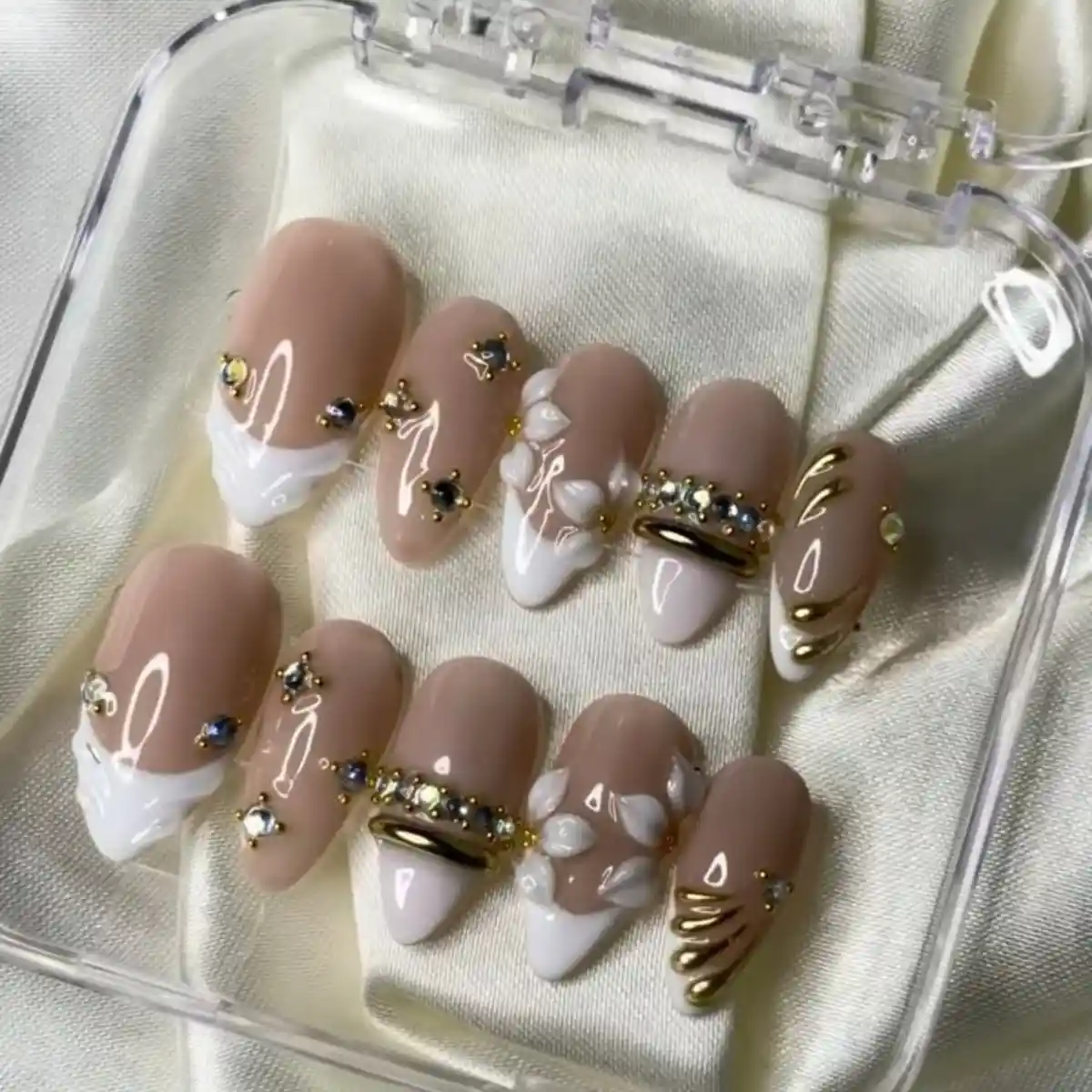 Nude and white set with wavy French tips, rhinestones, and gold accents