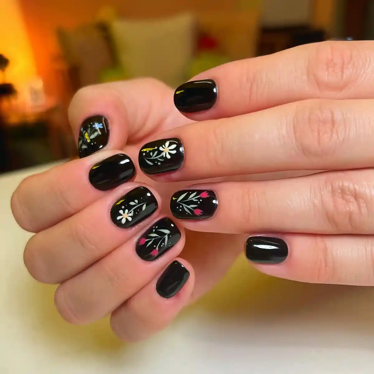 Short glossy black nails with painted floral motifs