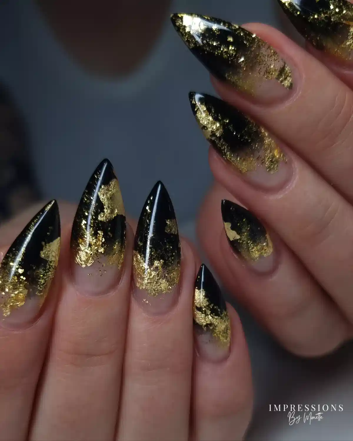 Black-and-nude pointed nails with irregular gold foil-like patches