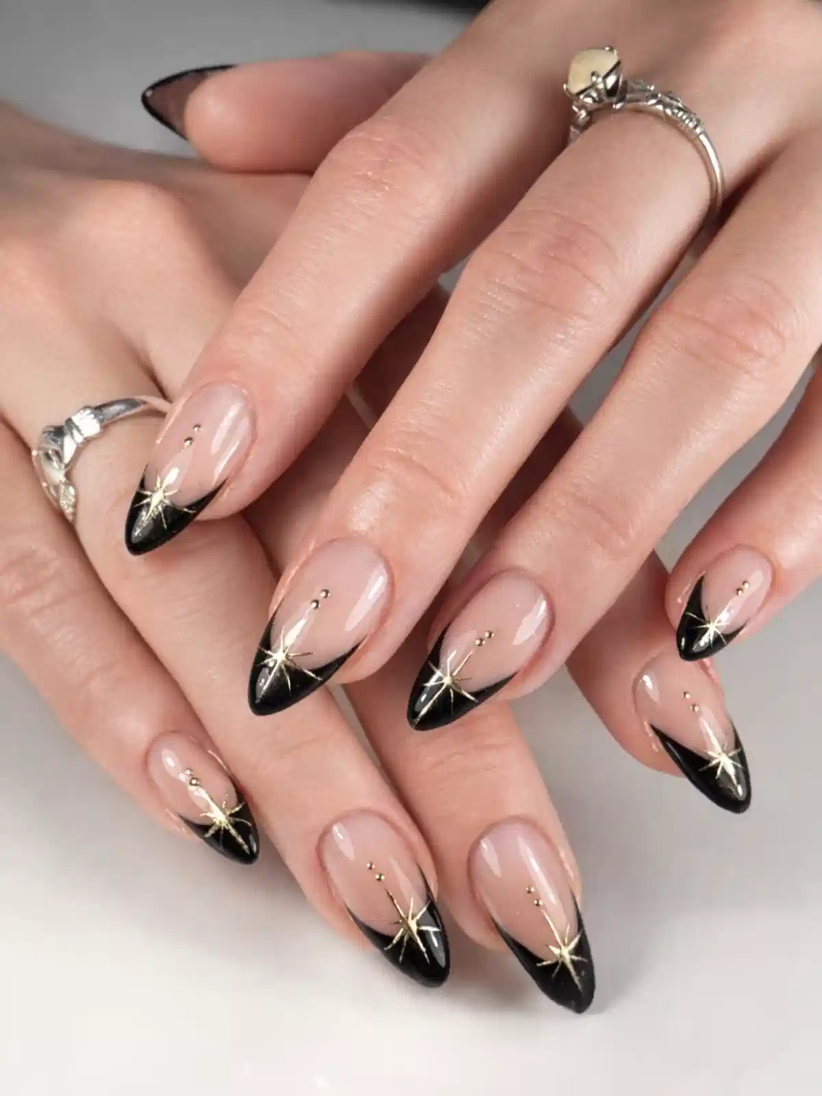 Nude-and-black French tips with gold starburst details