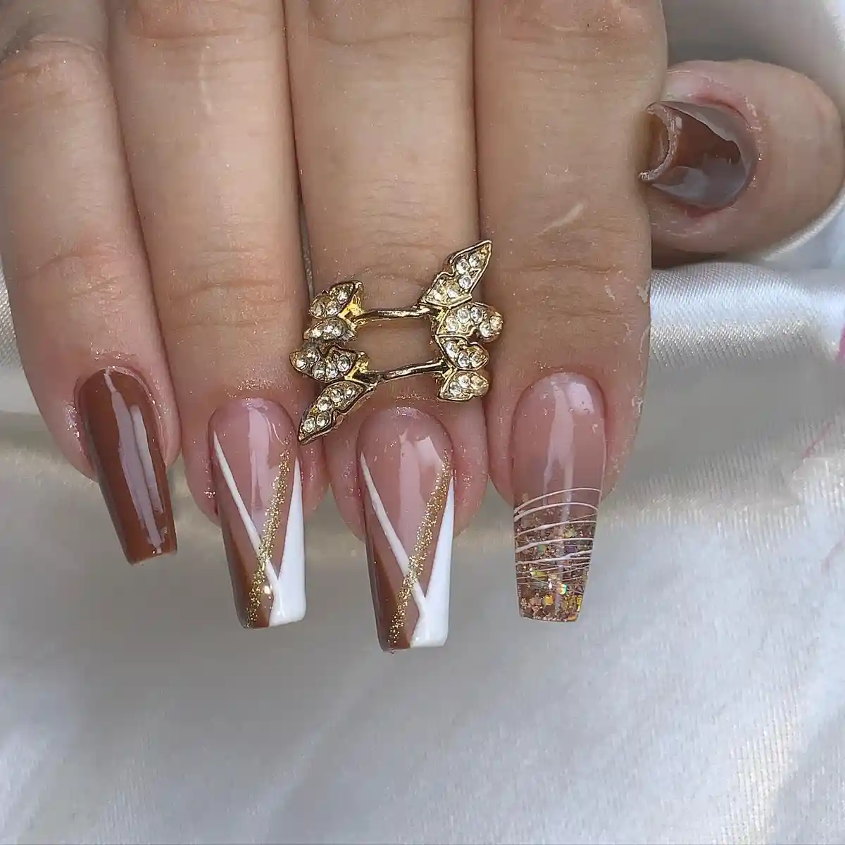 Coffin nails with brown-and-white diagonals and gold glitter striping