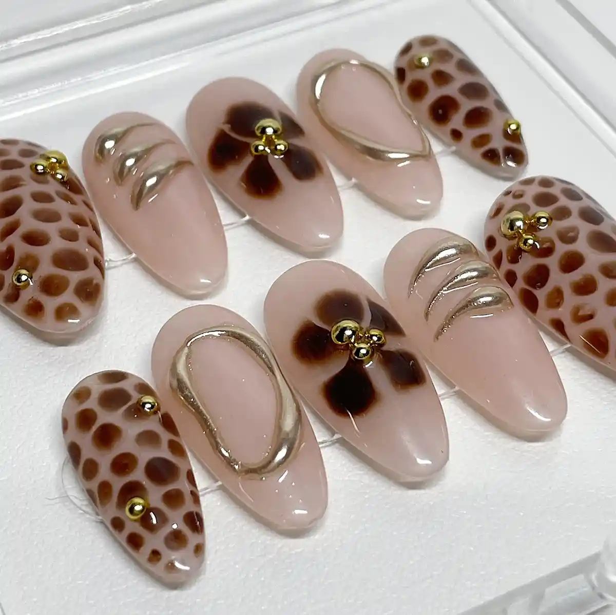 Press-on set with brown spots, floral accents, and gold 3D details