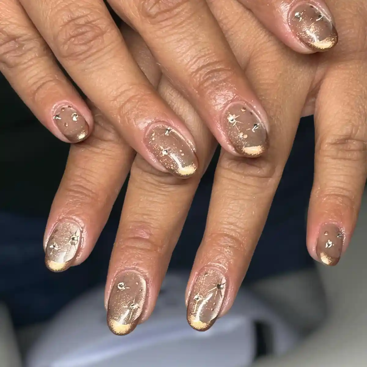 Sheer taupe nails with gold flecks and rhinestones