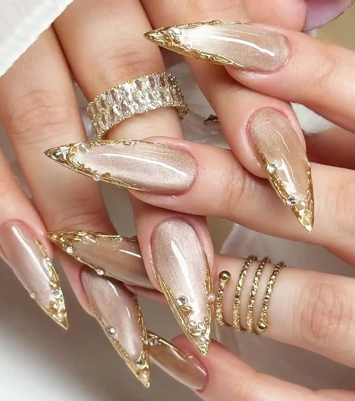 Stiletto shimmer nails with gold edging and pearls
