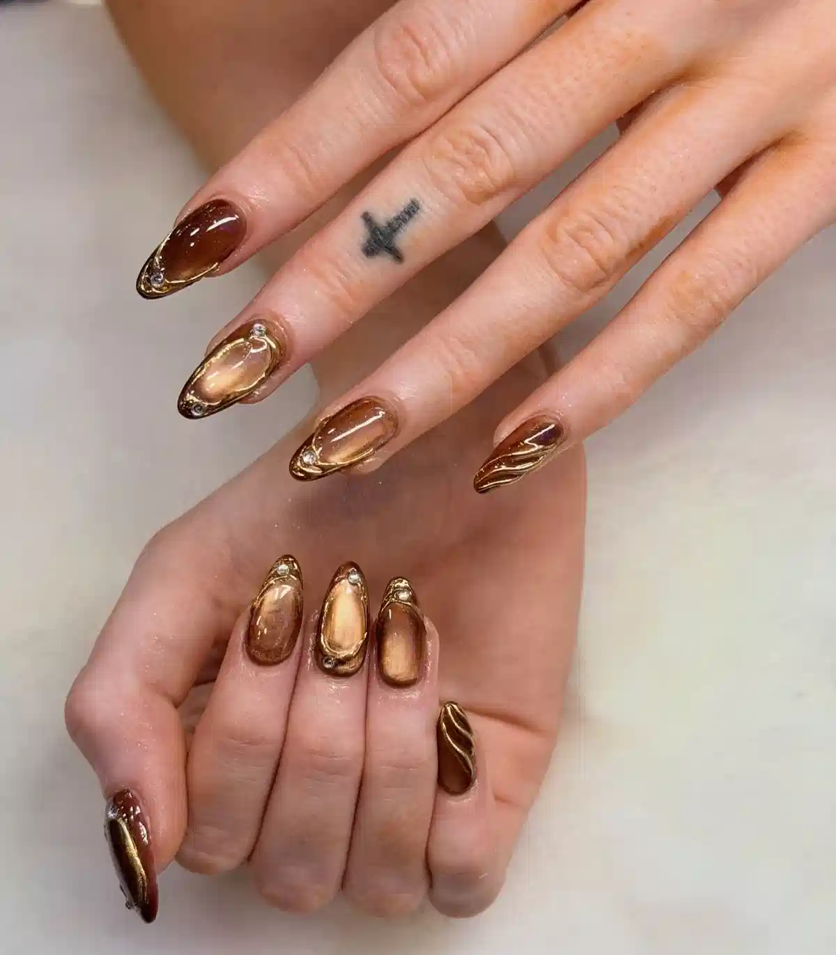 Brown-bronze reflective nails with gold outlines and rhinestones