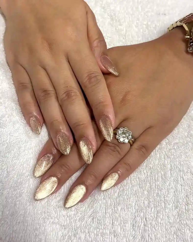 Long gold shimmer nails on a white towel backdrop