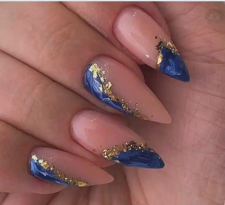 Nude almond nails with textured blue tips and gold accents