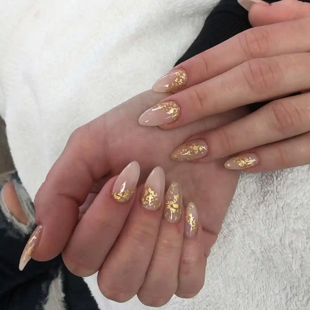 Nude almond nails with gold concentrated at the tips