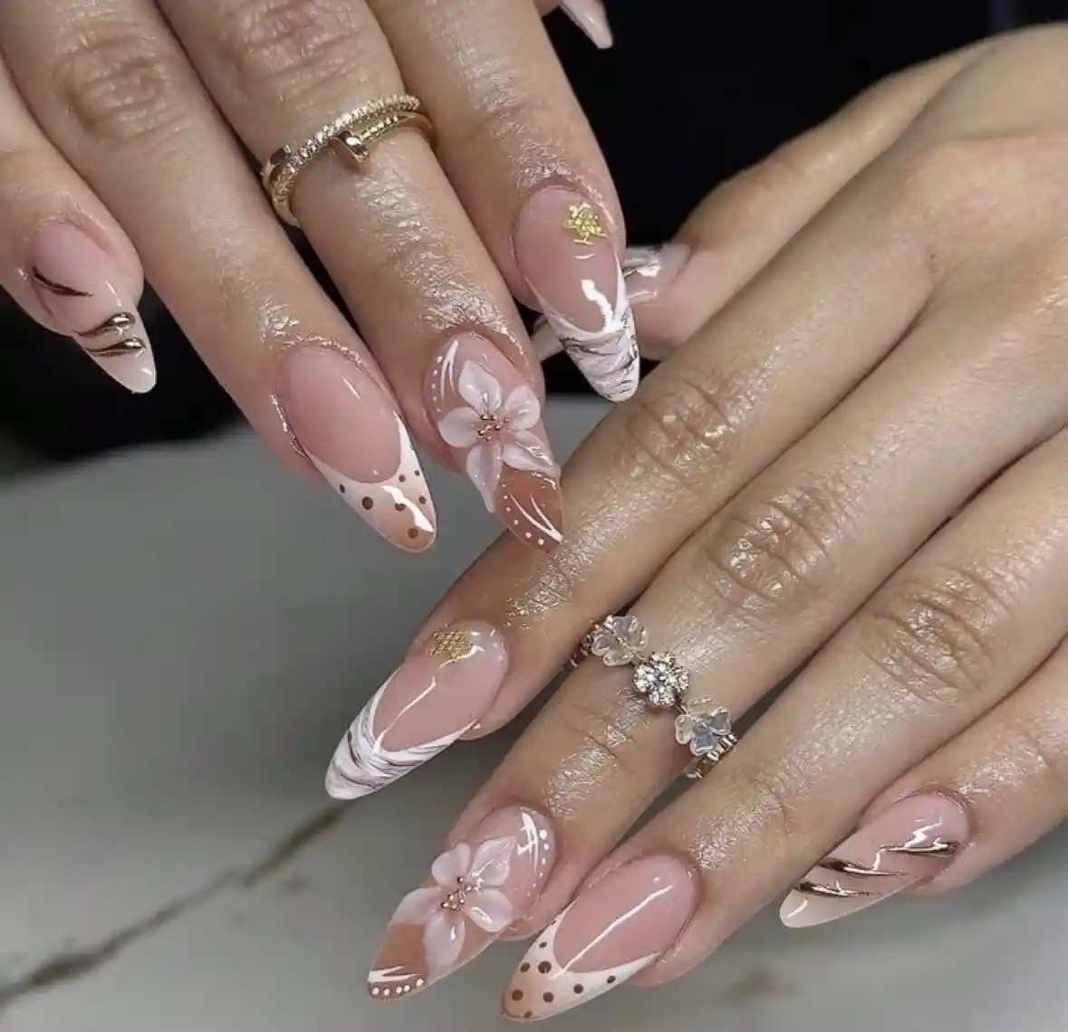 Nude-pink pointed nails with white swirls and 3D flower