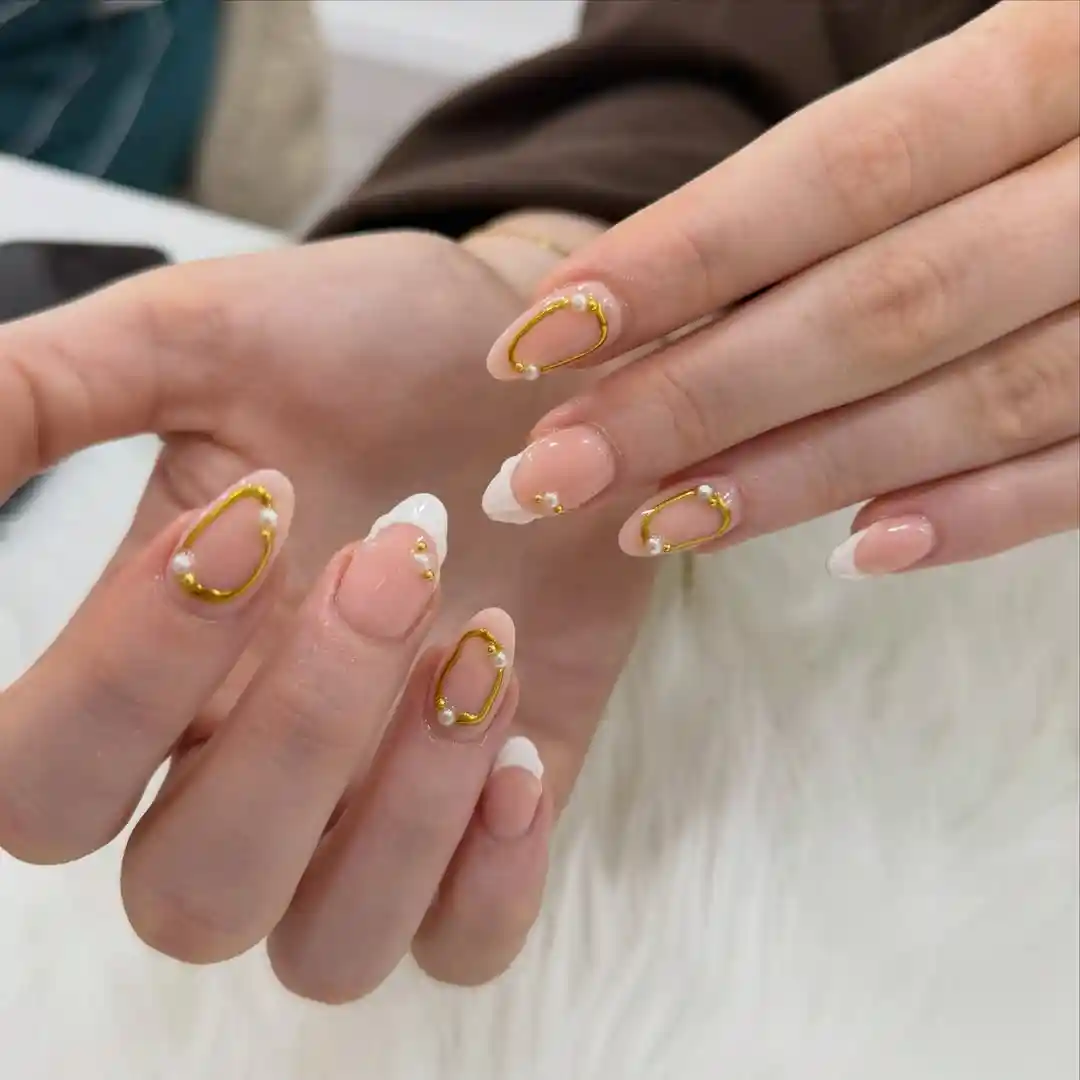 Nude French tips with gold oval outlines and pearl-like beads